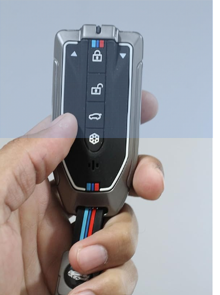 Car key fob with brand logo held in a hand against a light blue background