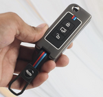 Hand holding a car key fob with buttons on a white background